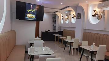 Interior modern d'un restaurant amb disposició de seients, una pantalla de televisió i aplics decoratius a la paret.