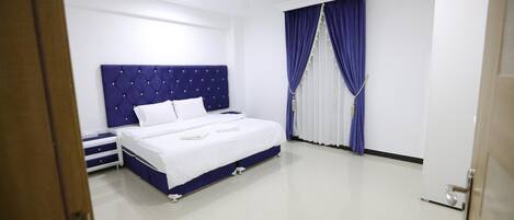 A bedroom with a large bed, a nightstand, and a wardrobe.
