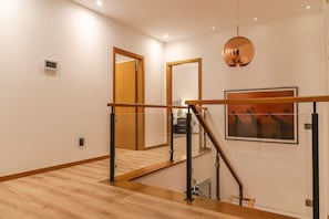 Experience the spacious interior with a wooden staircase, large mirror, and artwork, creating a comfortable and visually appealing atmosphere.