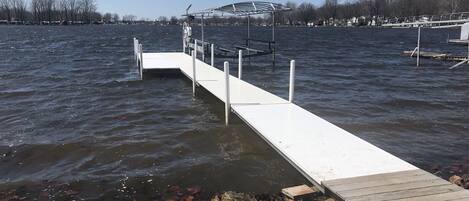 Une jetée s’avançant dans l’eau, avec une promenade couverte et une rangée de maisons en arrière-plan.