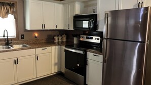 A kitchen with white cabinets, a stainless steel refrigerator, a microwave, and a stove. - Lakefront home on Little Barbee that sleeps 6 (Warsaw)