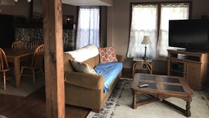 A living room with a sofa, a coffee table, a television, and a dining area with chairs and a table. - Lakefront home on Little Barbee that sleeps 6 (Warsaw)