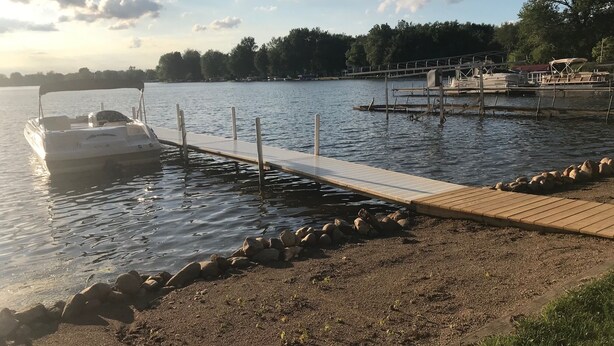 A boat docked at a pier with a wooden walkway leading to the water. - Lakefront home on Little Barbee that sleeps 6 (Warsaw)