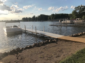 Ein Boot liegt an einem Steg, verbunden mit einer hölzernen Promenade, die zum Wasser führt.