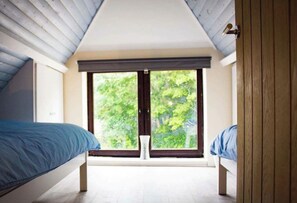 A bedroom with a large window, two beds, and a wooden door. - The Lodge Westmoor Farm (Market Rasen)