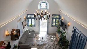 A spacious living area with a high ceiling, a chandelier, a sofa, a coffee table, and a patterned floor. - Bliss Mansion with Swimming Pool, Cave Hot Tube & Sunset view  (Pyrgos Kallistis)