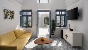 A modern living room with a yellow sofa, a round wooden coffee table, and a white cabinet with a TV mounted on the wall. - Bliss Mansion with Swimming Pool, Cave Hot Tube & Sunset view  (Pyrgos Kallistis)