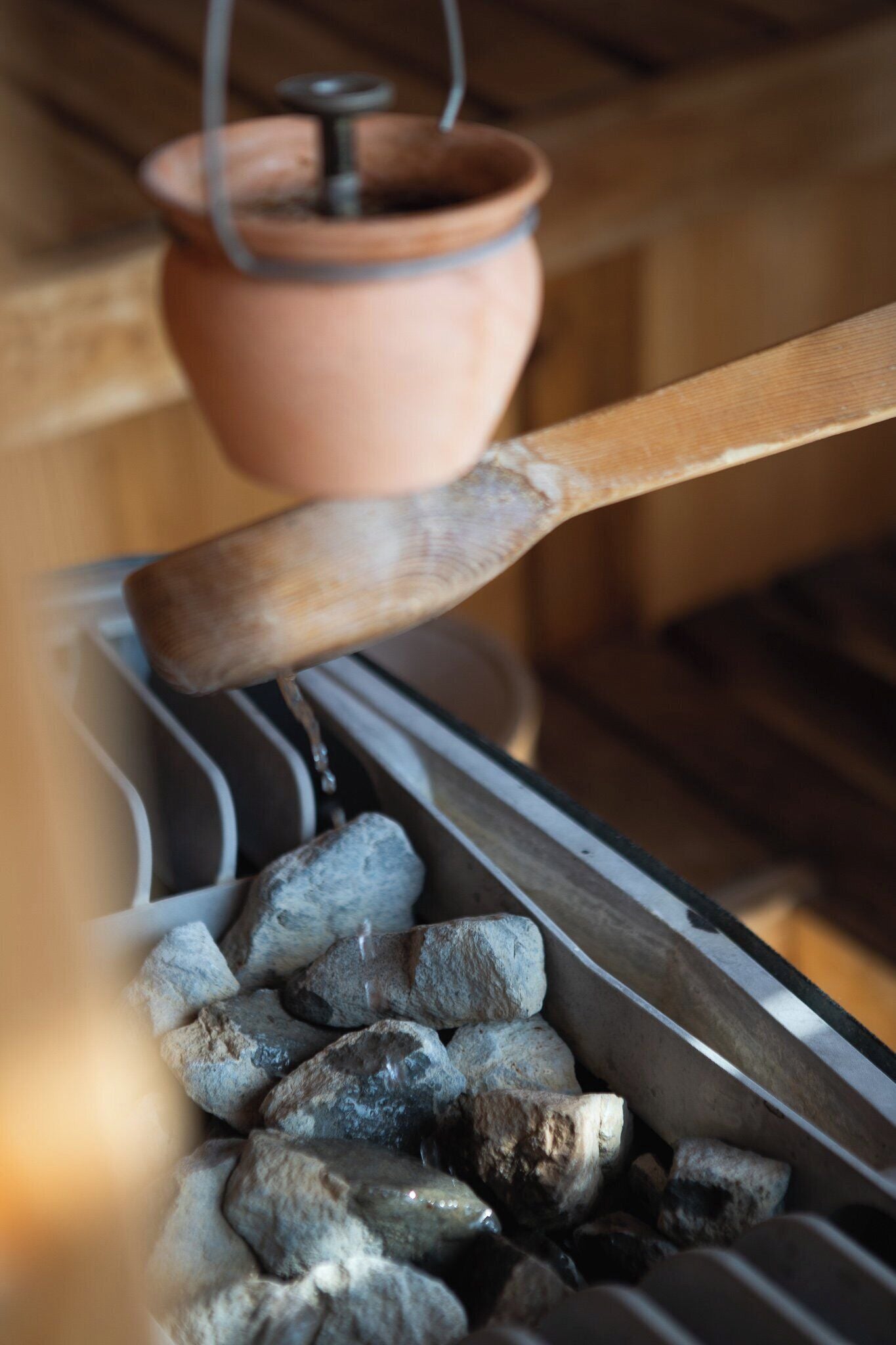 A close-up of a wooden spoon stirring charcoal in a metal container.