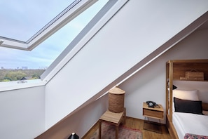 A modern bedroom with a skylight, a wooden bedside table, a small rug, and a bed with a headboard. - Bryggen Guldsmeden  (Copenhagen)