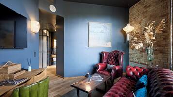 A modern living room with a flat-screen TV, a wooden coffee table, a red leather sofa, and a brick wall.