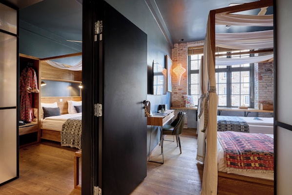 A modern room with a bed, desk, and chair, wooden flooring, and a view of the outside through a window. - Bryggen Guldsmeden (Copenhagen)