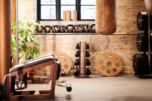 Ein Fitnessstudio mit Kettlebells, einer Hantelbank und einem Boxsack.