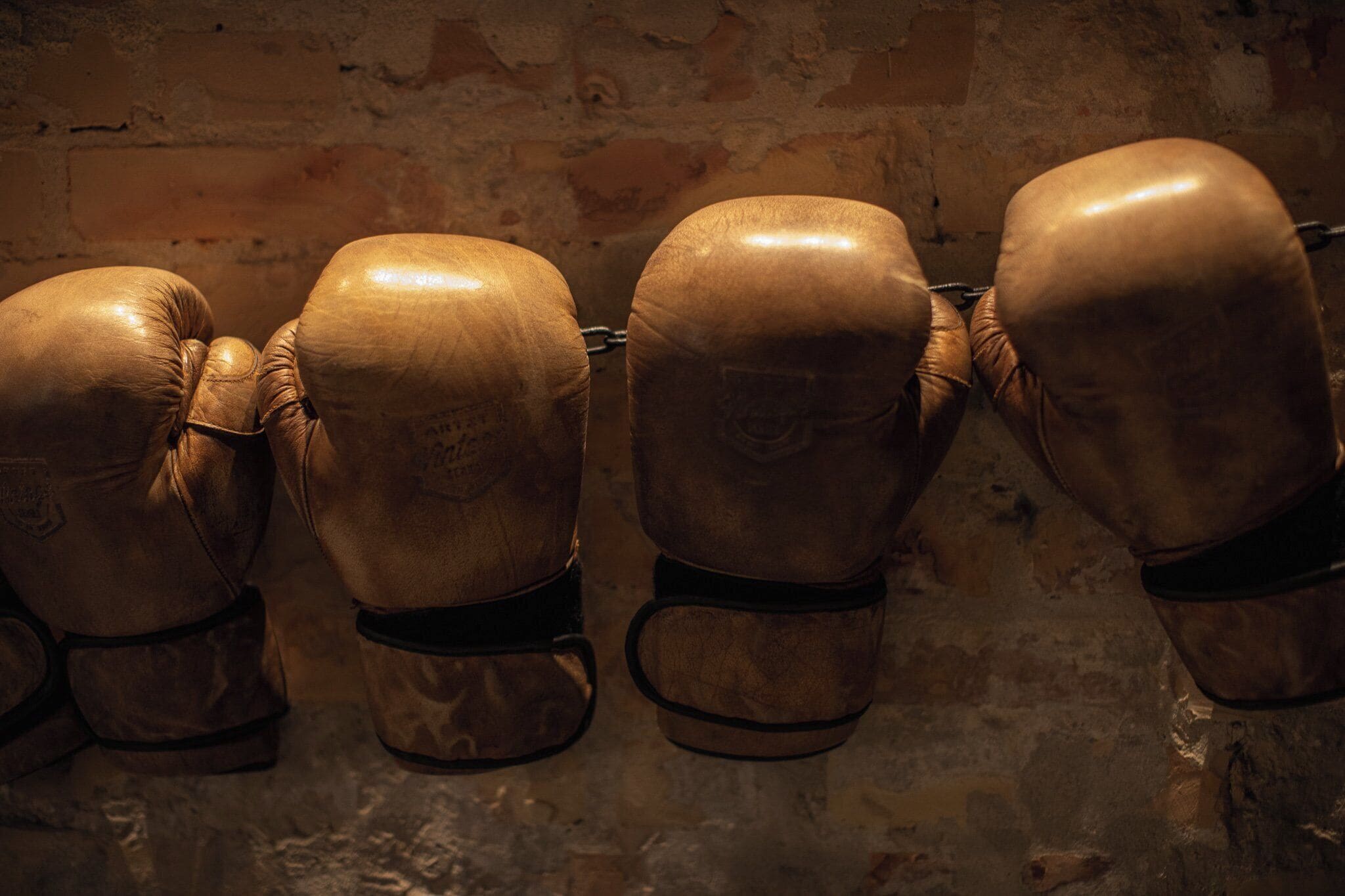 Vier Paar Boxhandschuhe hängen an einer Wand.
