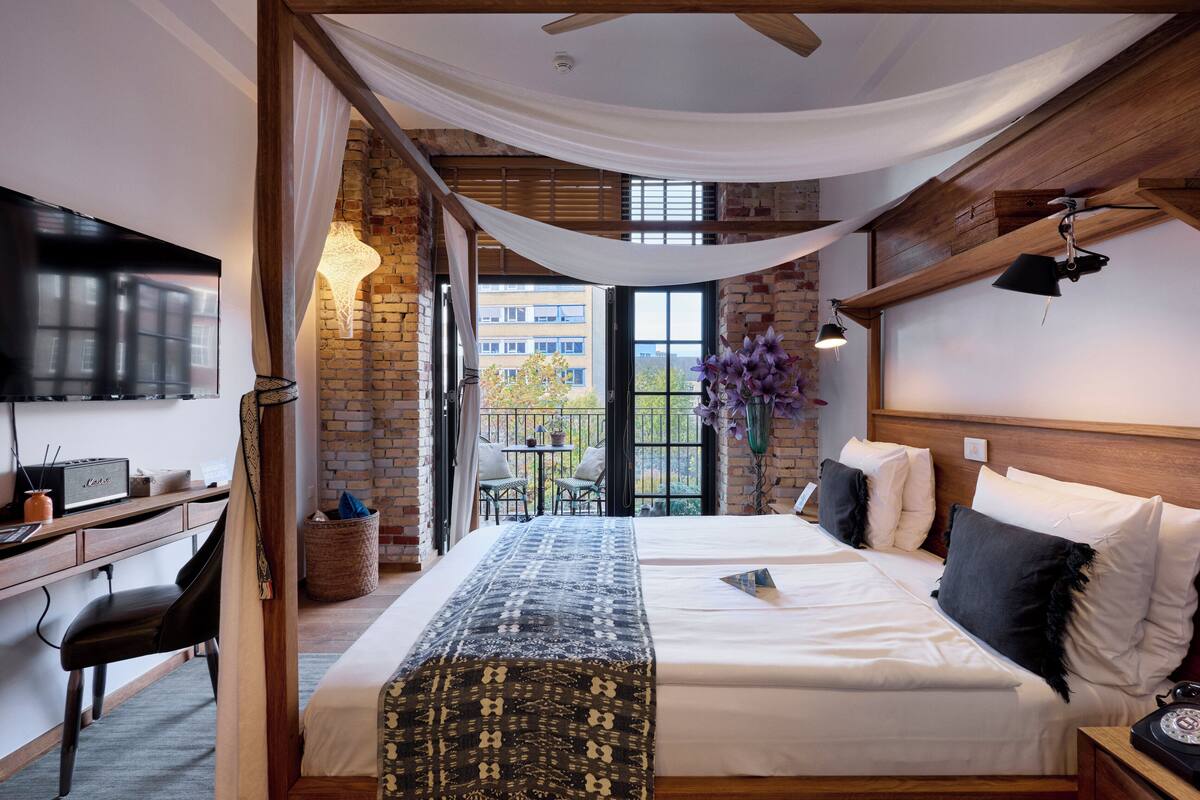 A hotel room with a bed, desk, and a TV.