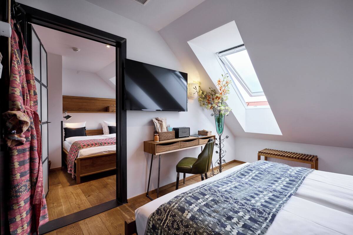 Une chambre à coucher comprenant un lit, un bureau, une chaise, un téléviseur et une fenêtre de toit.
