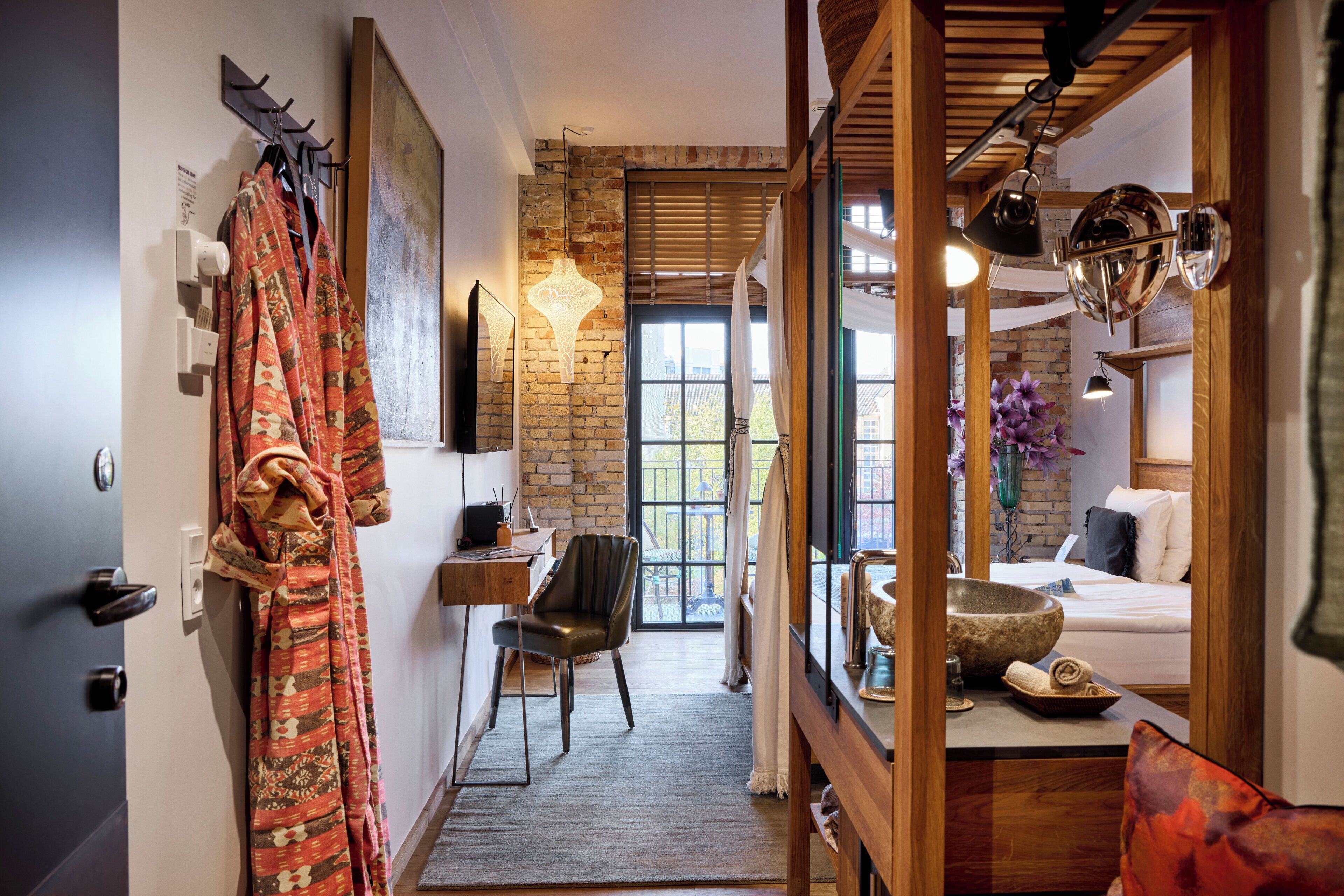 Habitación de hotel con pared de ladrillo, techo de madera, cama, escritorio y una silla.