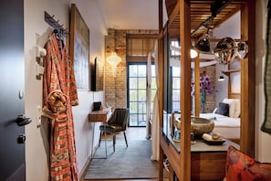 A hotel room with a brick wall, a wooden ceiling, a bed, a desk, and a chair. - Bryggen Guldsmeden  (Copenhagen)