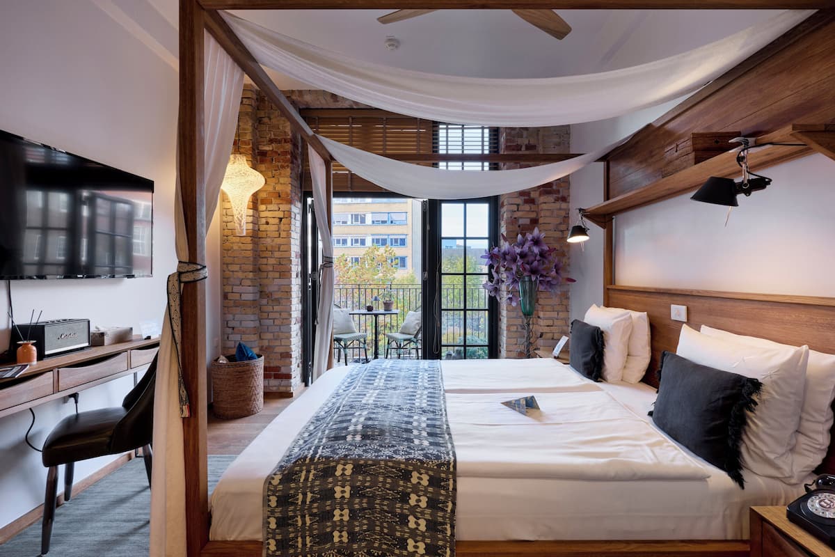 A hotel room with a bed, desk, and a TV.