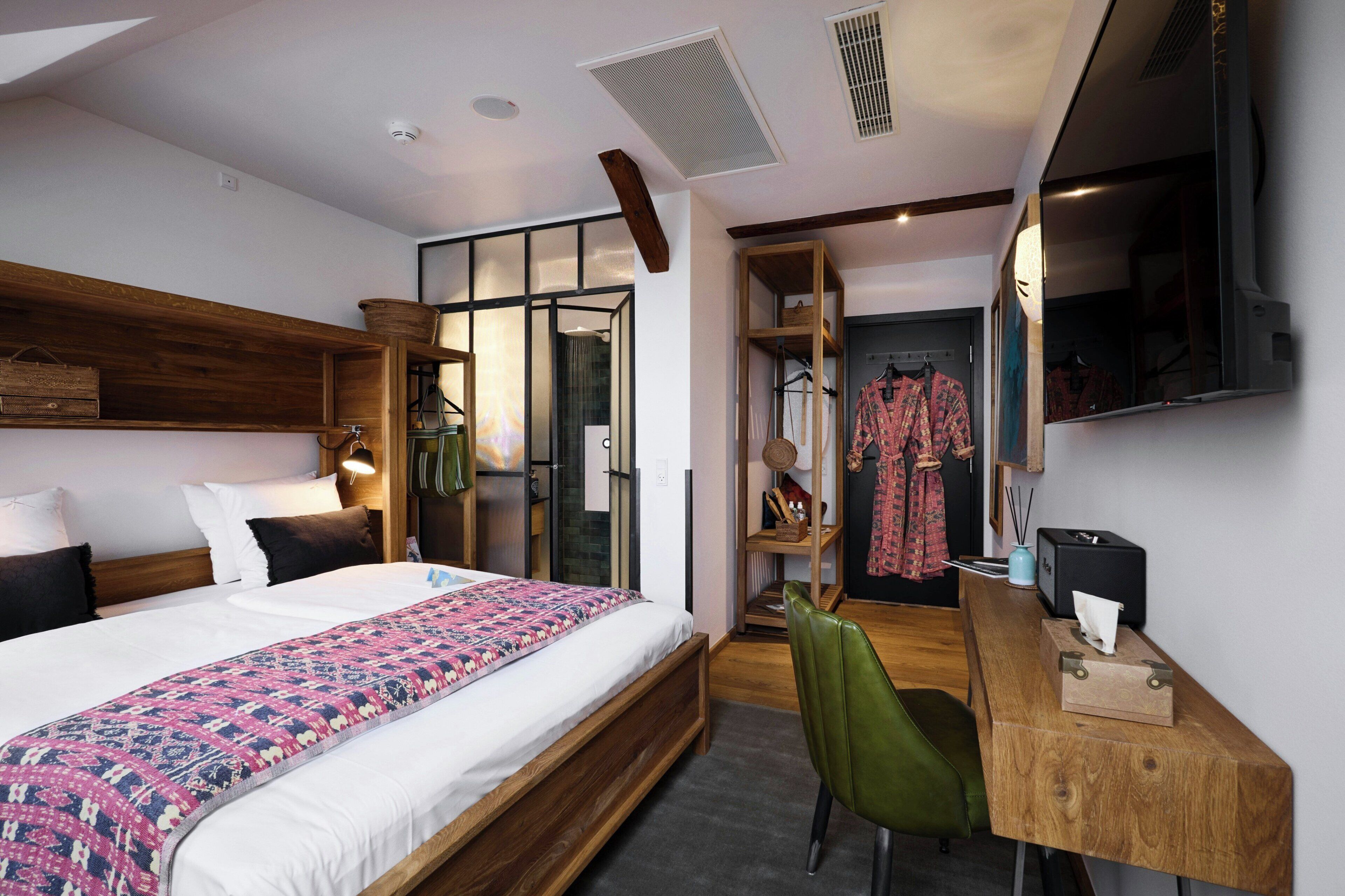 Une chambre d’hôtel comprenant un lit, un bureau, une chaise, une armoire et un miroir.