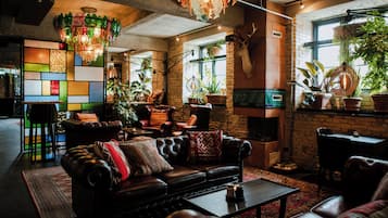 Ein gemütlicher Loungebereich mit Ledersofas, einem Couchtisch und verschiedenen topfgepflanzten Pflanzen.