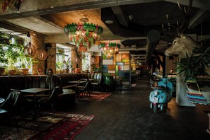 Un restaurante con cabinas, mesas, luces colgantes y una moto.