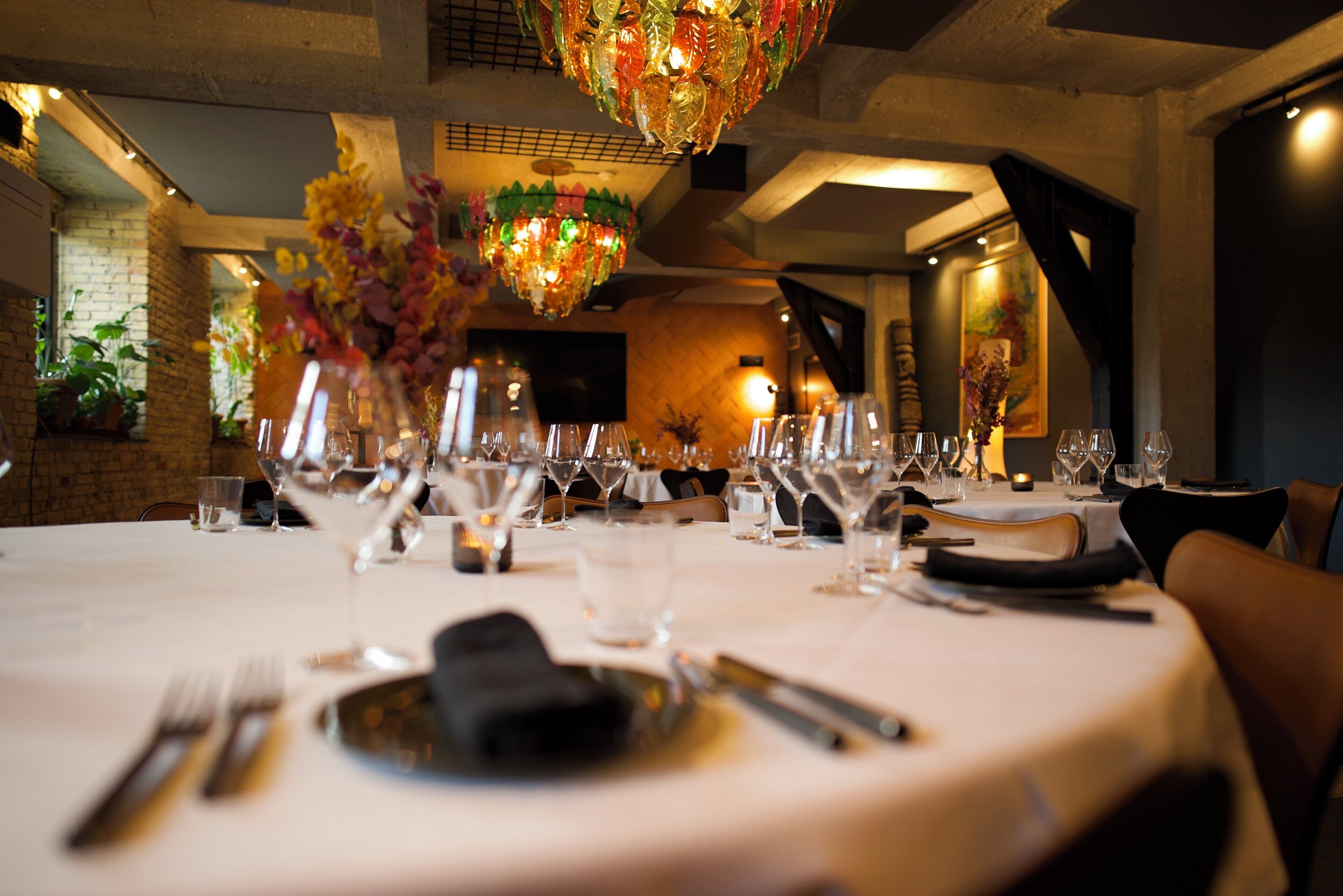A dining table set with wine glasses, cutlery, and a vase of flowers.