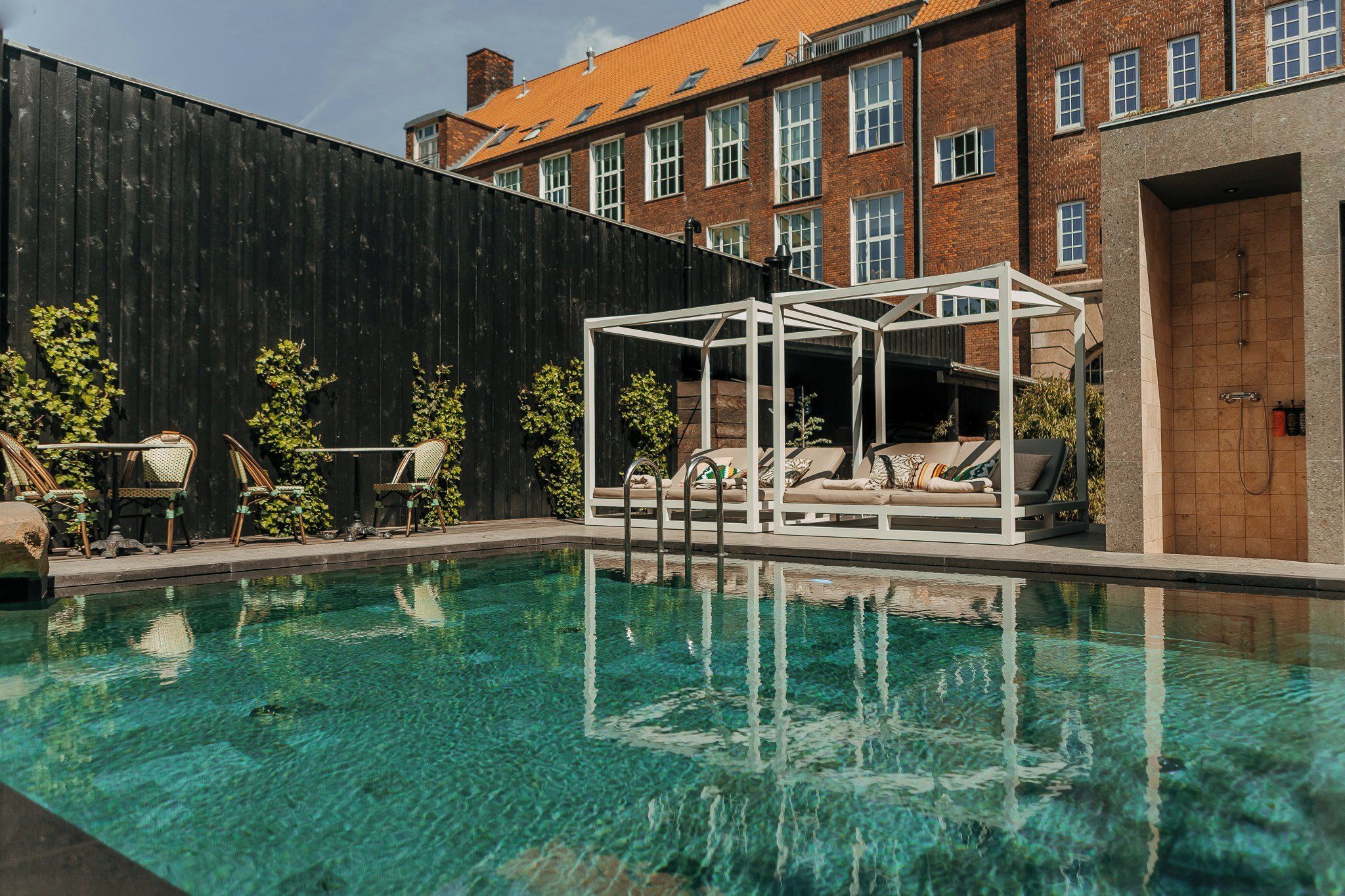 En pool med liggestole og et pergola-område.
