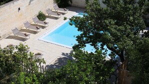 Un área de piscina con sillas de descanso y un muro de piedra.