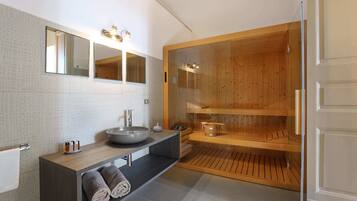 Une salle de bain moderne avec un grand miroir, un lavabo et un sauna.