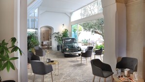 Un amplio espacio interior con asientos modernos, un coche antiguo y ventanas grandes que ofrecen vistas al exterior.