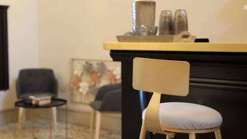 A modern living room with a black sofa, a small round table with a book, and a decorative painting.