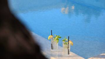 Dos vasos de una bebida con hojas de menta y rodajas de limón en una zona junto a la piscina.