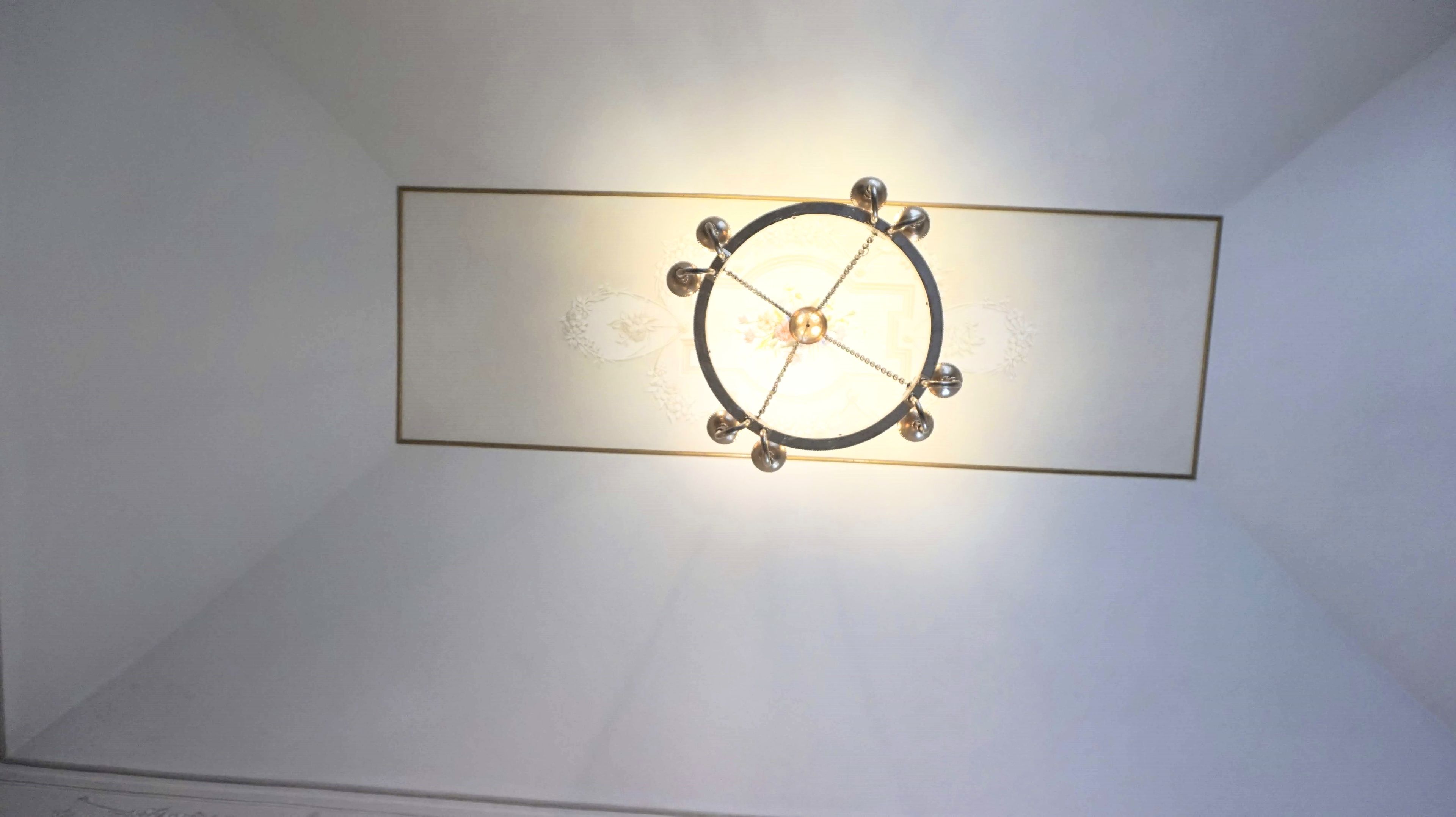 Un luminaire de plafond composé d’un globe central et de quatre ampoules suspendues.