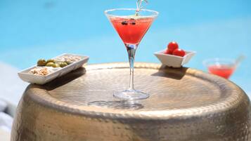 A martini glass with a cherry garnish on a textured metal table.