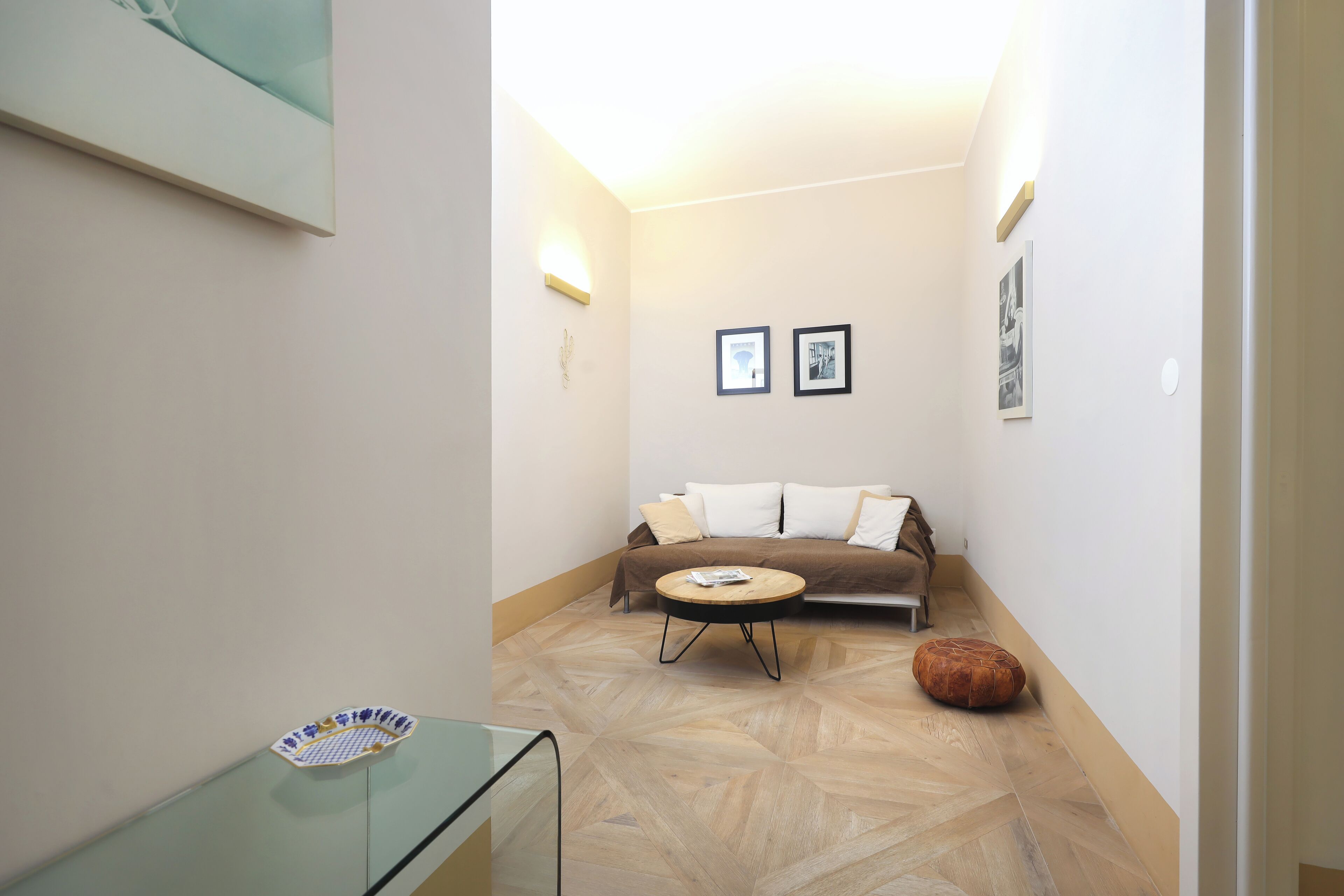 Un soggiorno moderno con un divano, un tavolino rotondo e un tavolo in vetro con una ciotola decorativa.