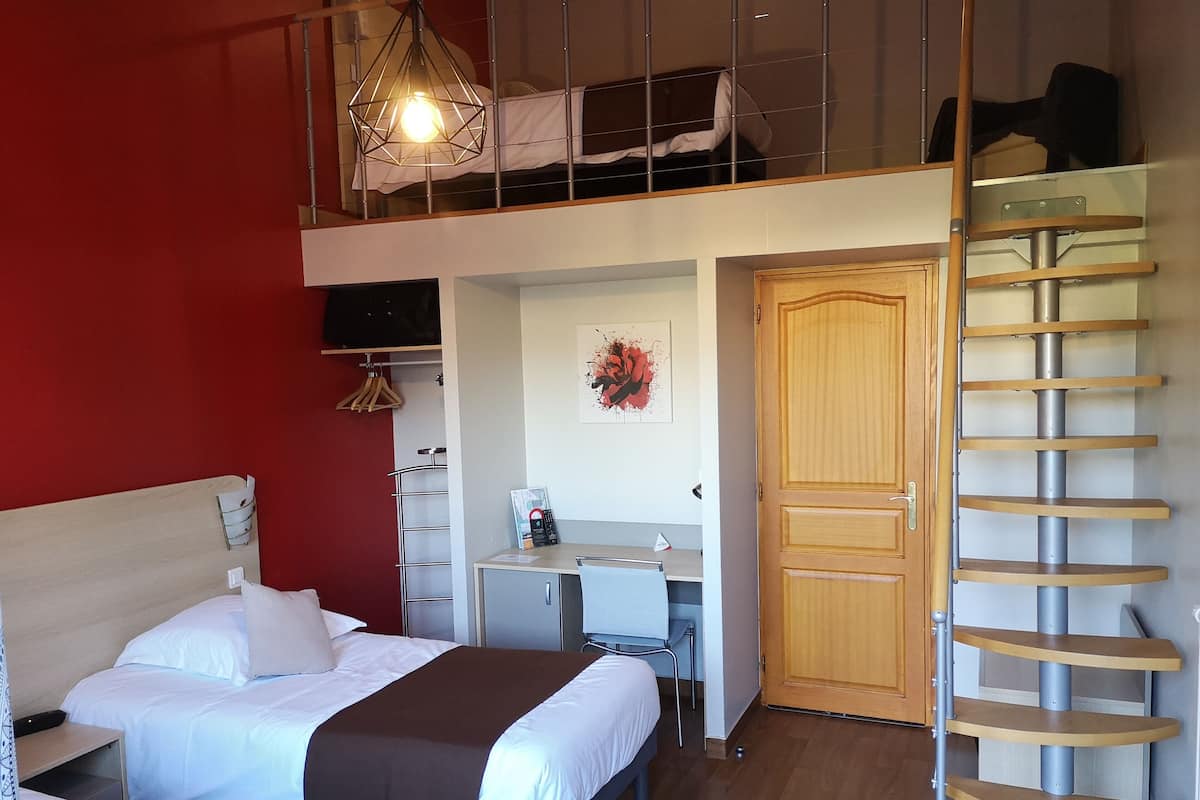 Un dormitorio con dos camas, un escritorio, un armario y una escalera en espiral.