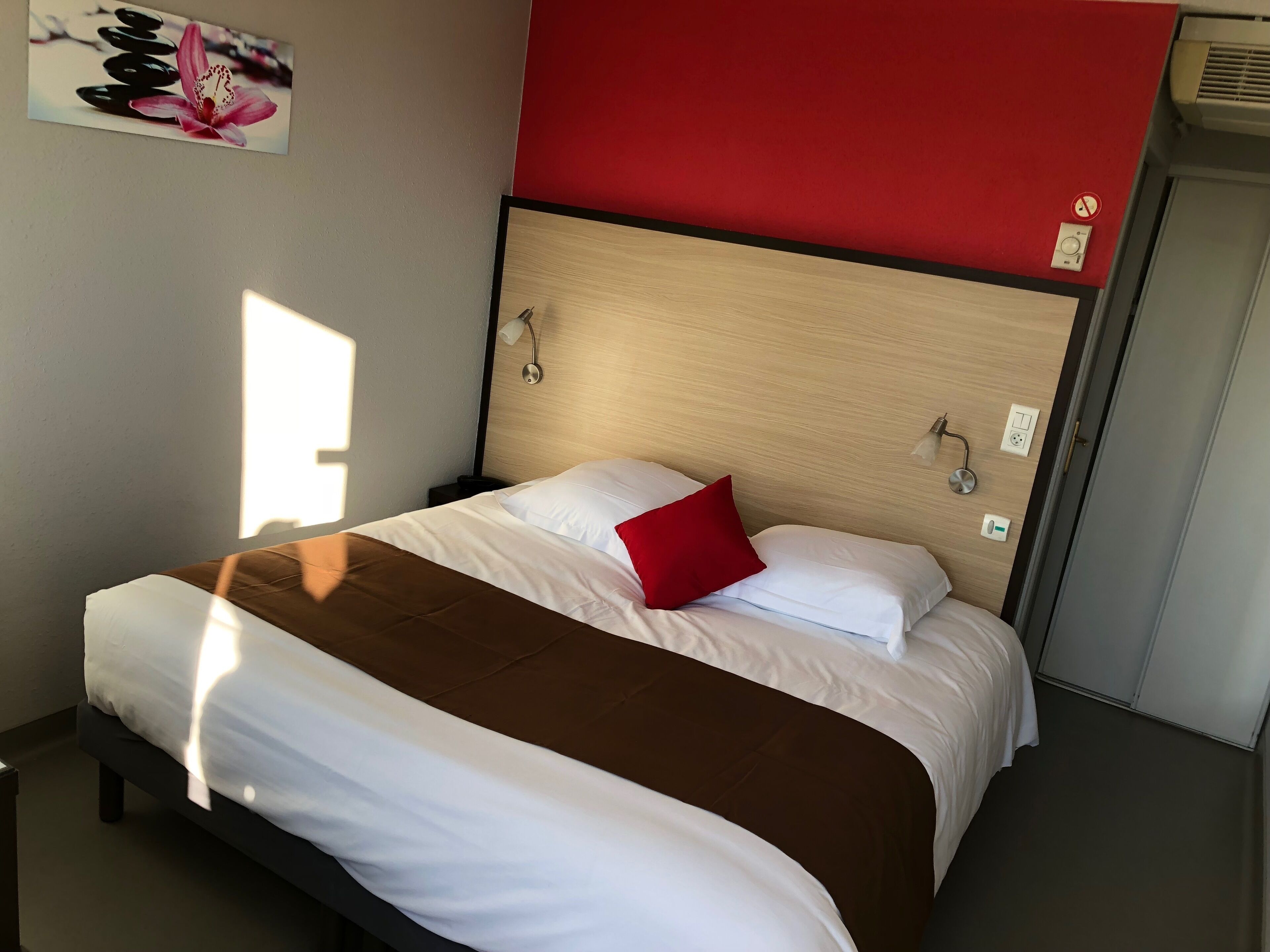 Habitació d'hotel amb un llit, una paret vermella i una finestra.