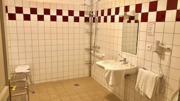 Un baño con un lavabo blanco, un espejo, una ducha y un perchero para toallas.