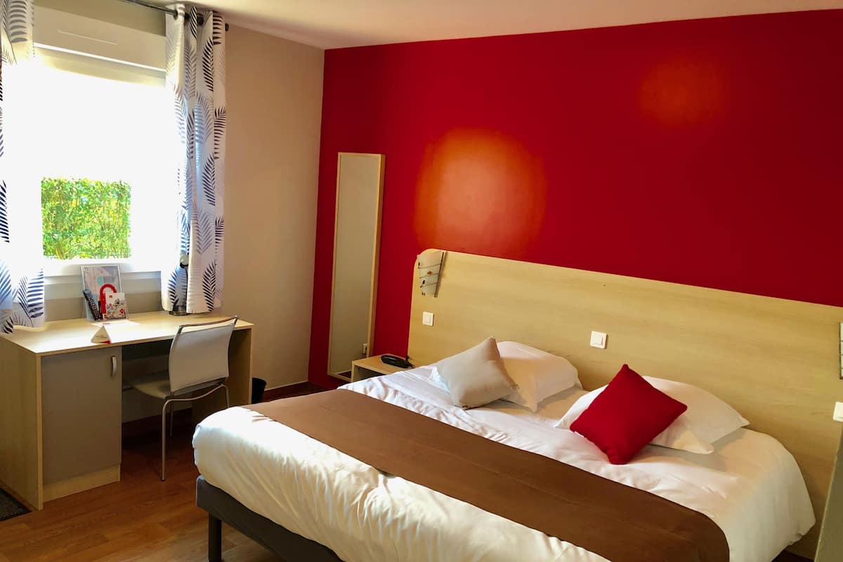 Una habitación de hotel con una cama, un escritorio y una silla.