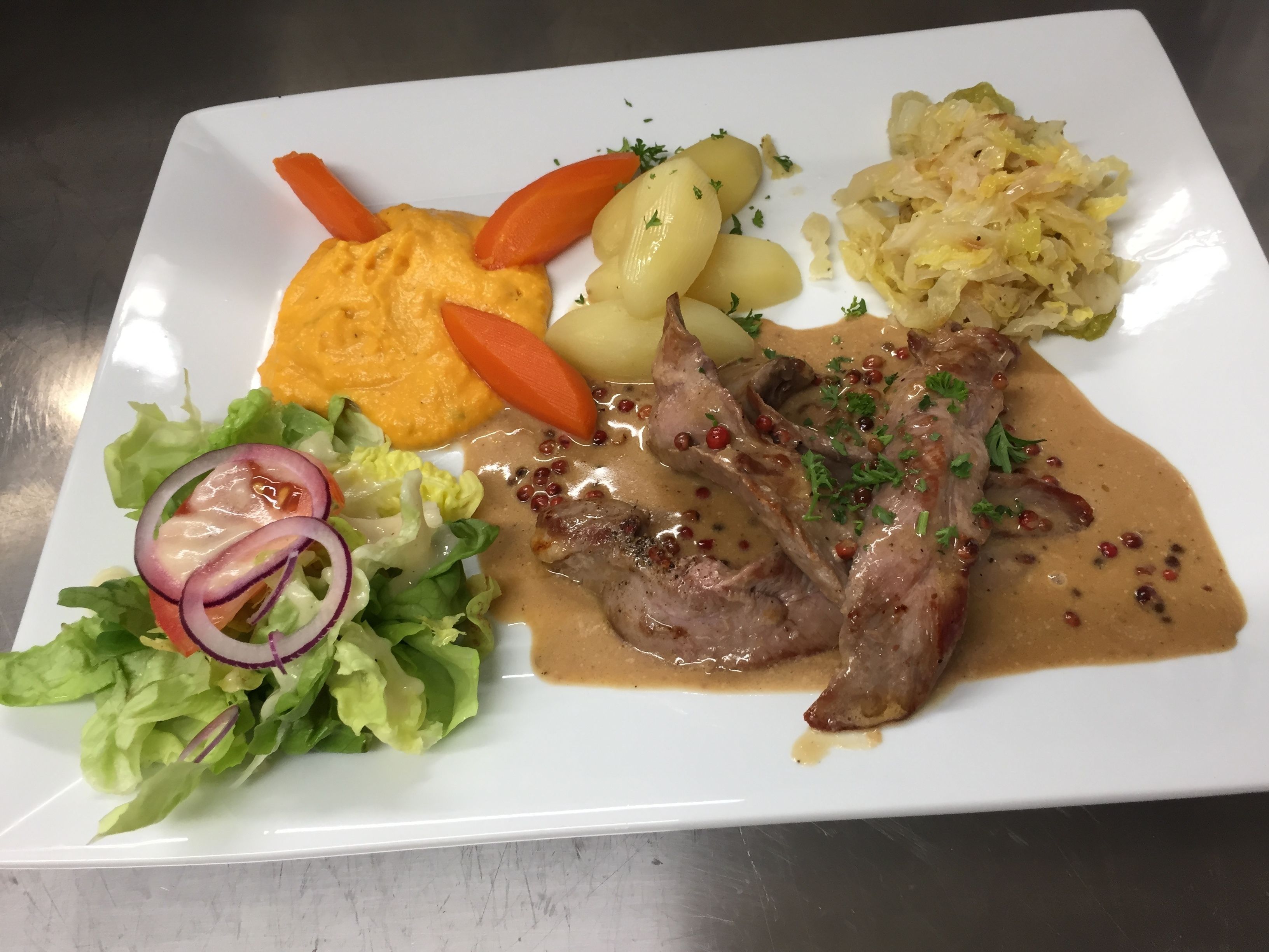 A plate with meat, potatoes, carrots, and a salad.