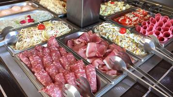 A buffet with various food options including meats, salads, and rice dishes.