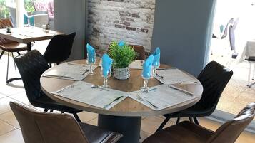 A round table with a clock on the wall behind it, surrounded by chairs.