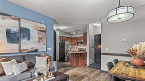 A modern living room with a sofa, coffee table, and artwork on the wall. - Experience Cozy Rockies Escape w/ Pool & Hot tub (Canmore)