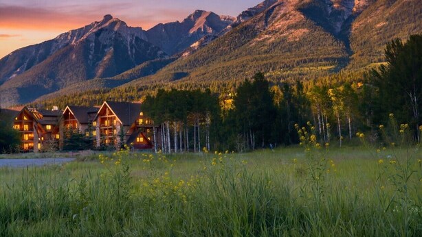 A lodge with multiple log cabins, surrounded by a forest and mountains. - Experience Cozy Rockies Escape w/ Pool & Hot tub (Canmore)