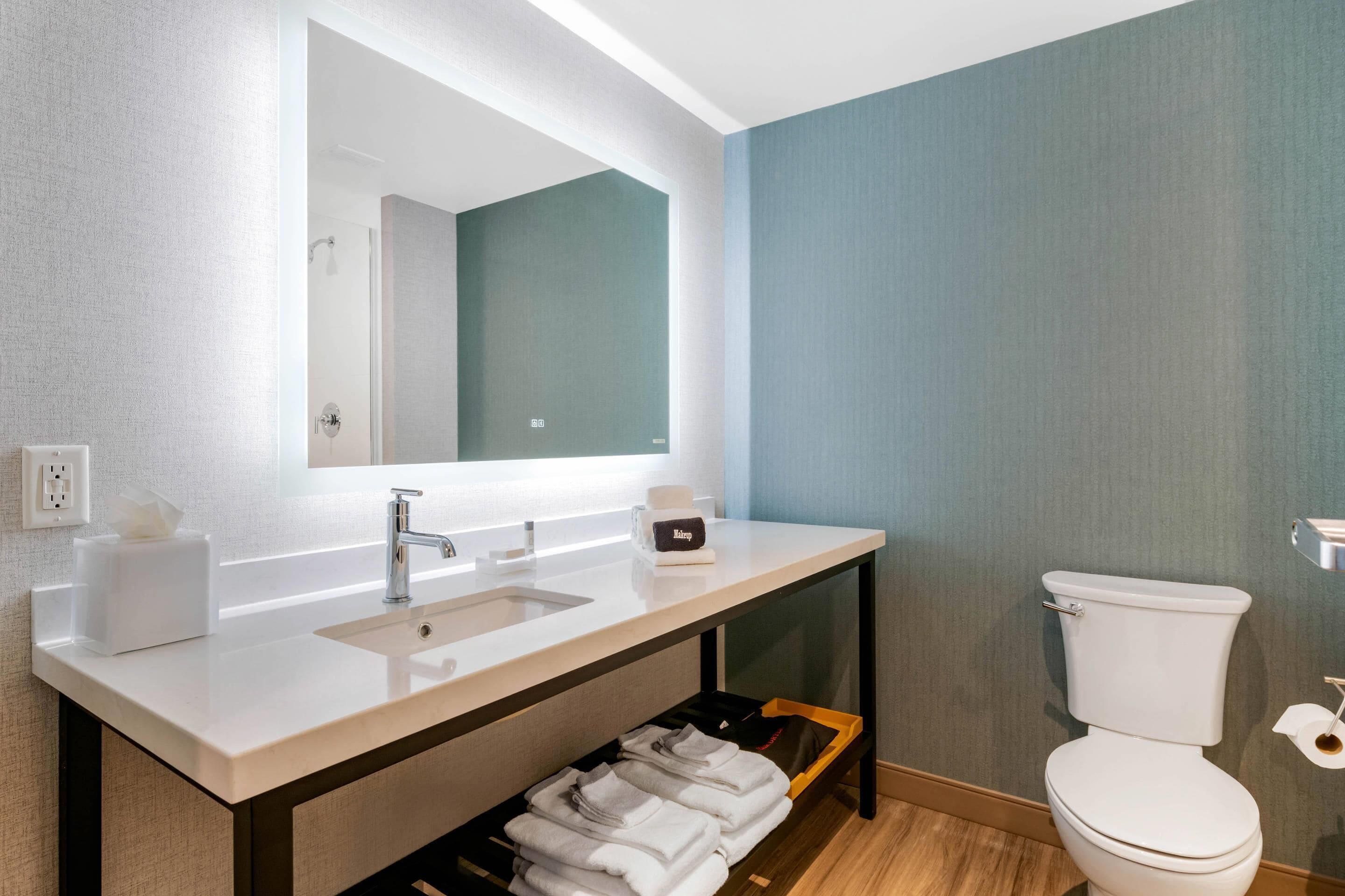 A modern bathroom with a white sink, mirror, and toilet.