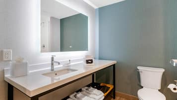 A modern bathroom with a white sink, mirror, and toilet.