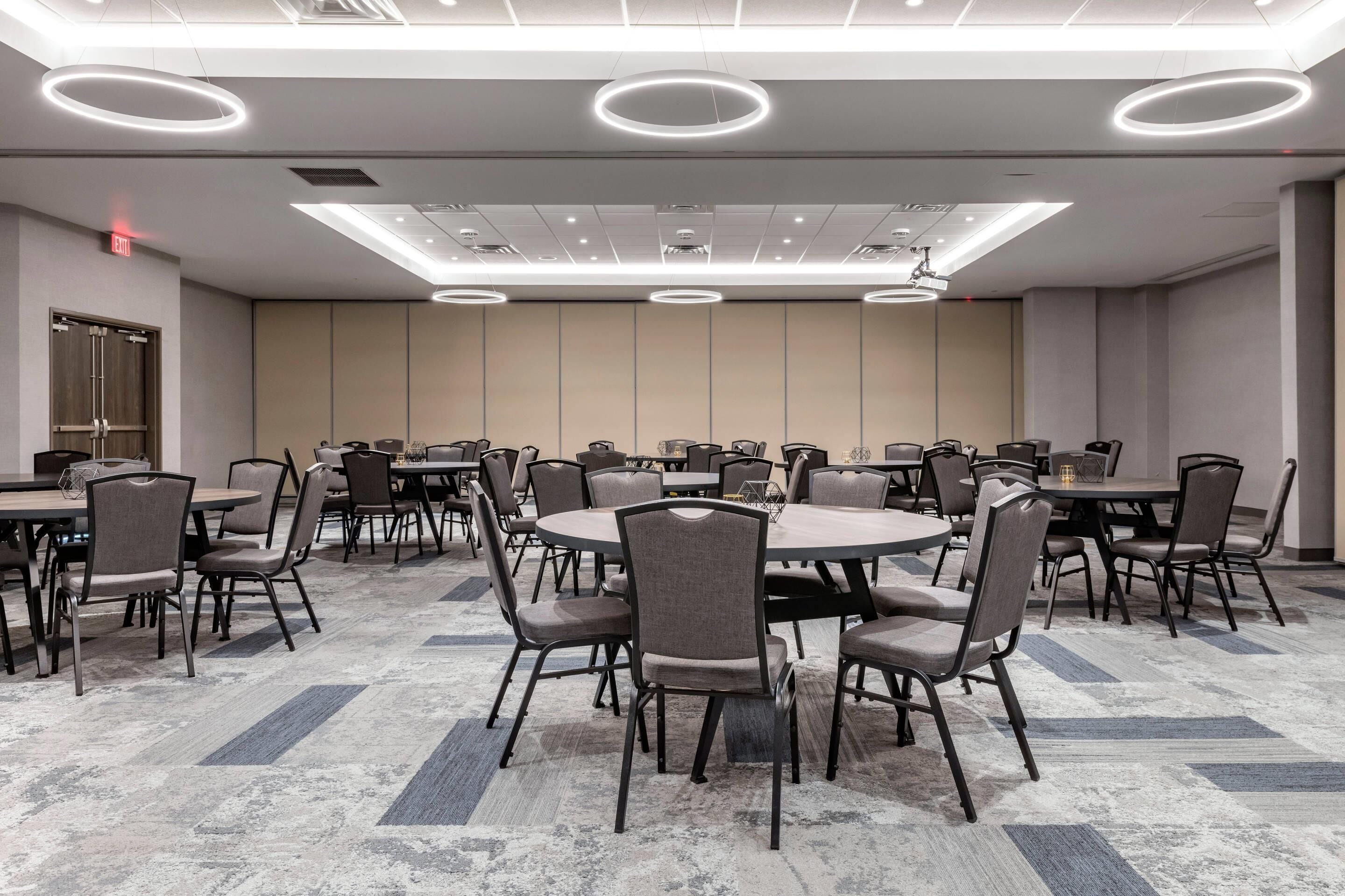 A conference room with round tables, chairs, and modern lighting fixtures.