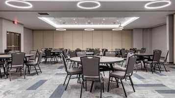 A conference room with round tables, chairs, and modern lighting fixtures.