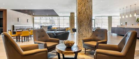 A modern lounge area with leather armchairs, a round coffee table, and a large wooden pillar.