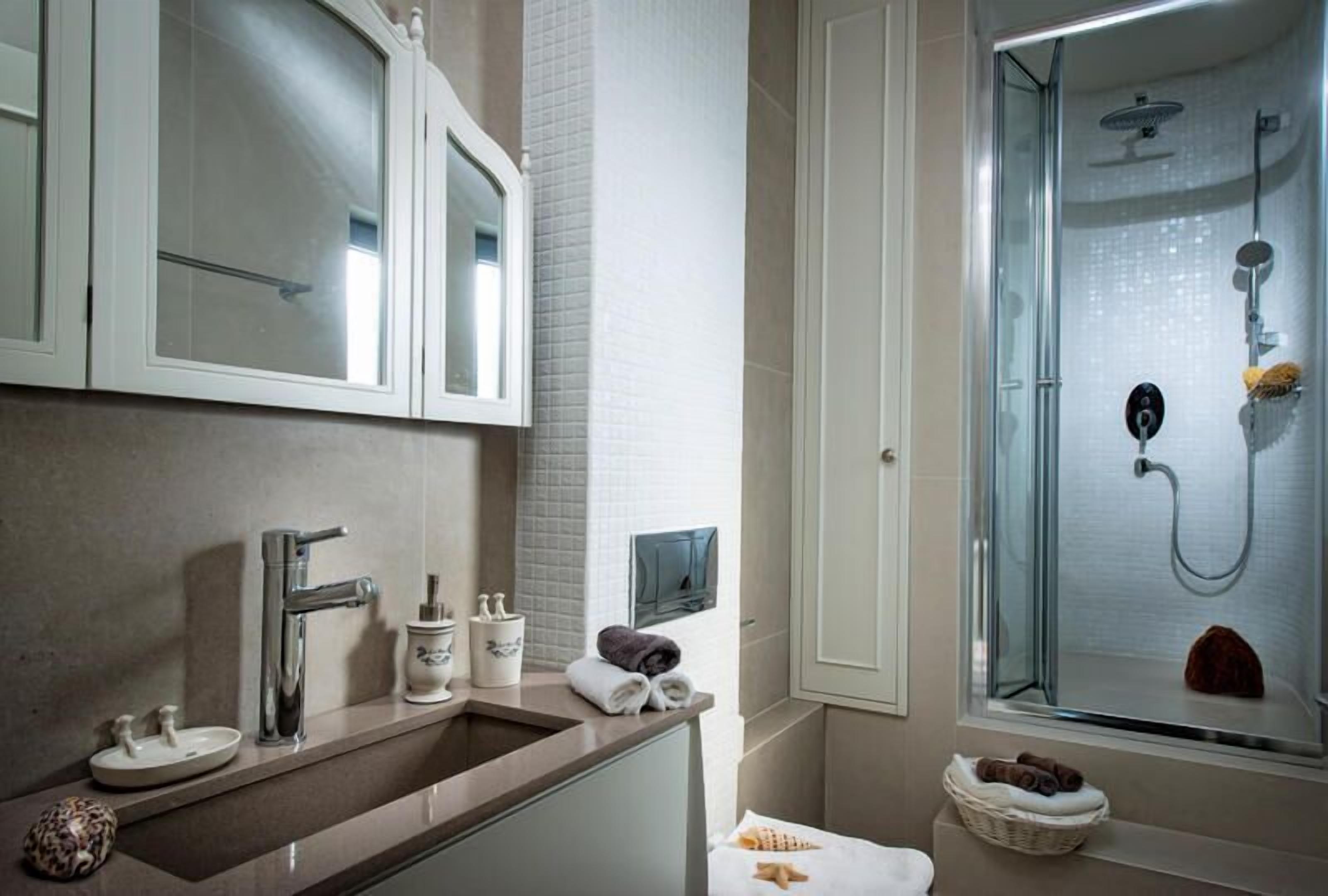 A modern bathroom with a glass-enclosed shower, a vanity with a sink and mirror, and neatly arranged towels.